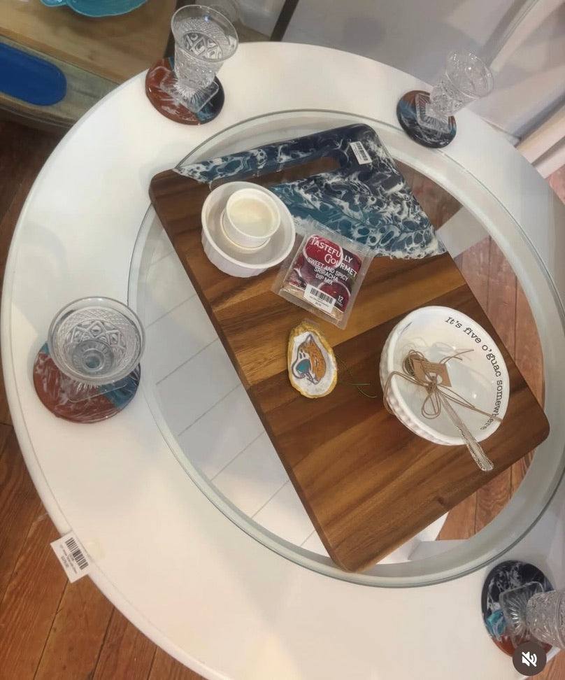 Wooden cutting board with various items on a round glass table