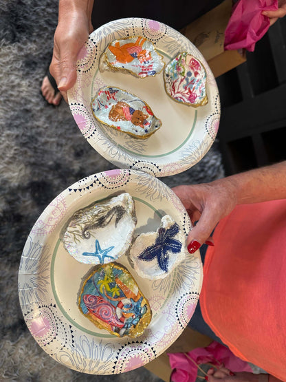 Two decorative plates with painted sea-themed designs held by a person.