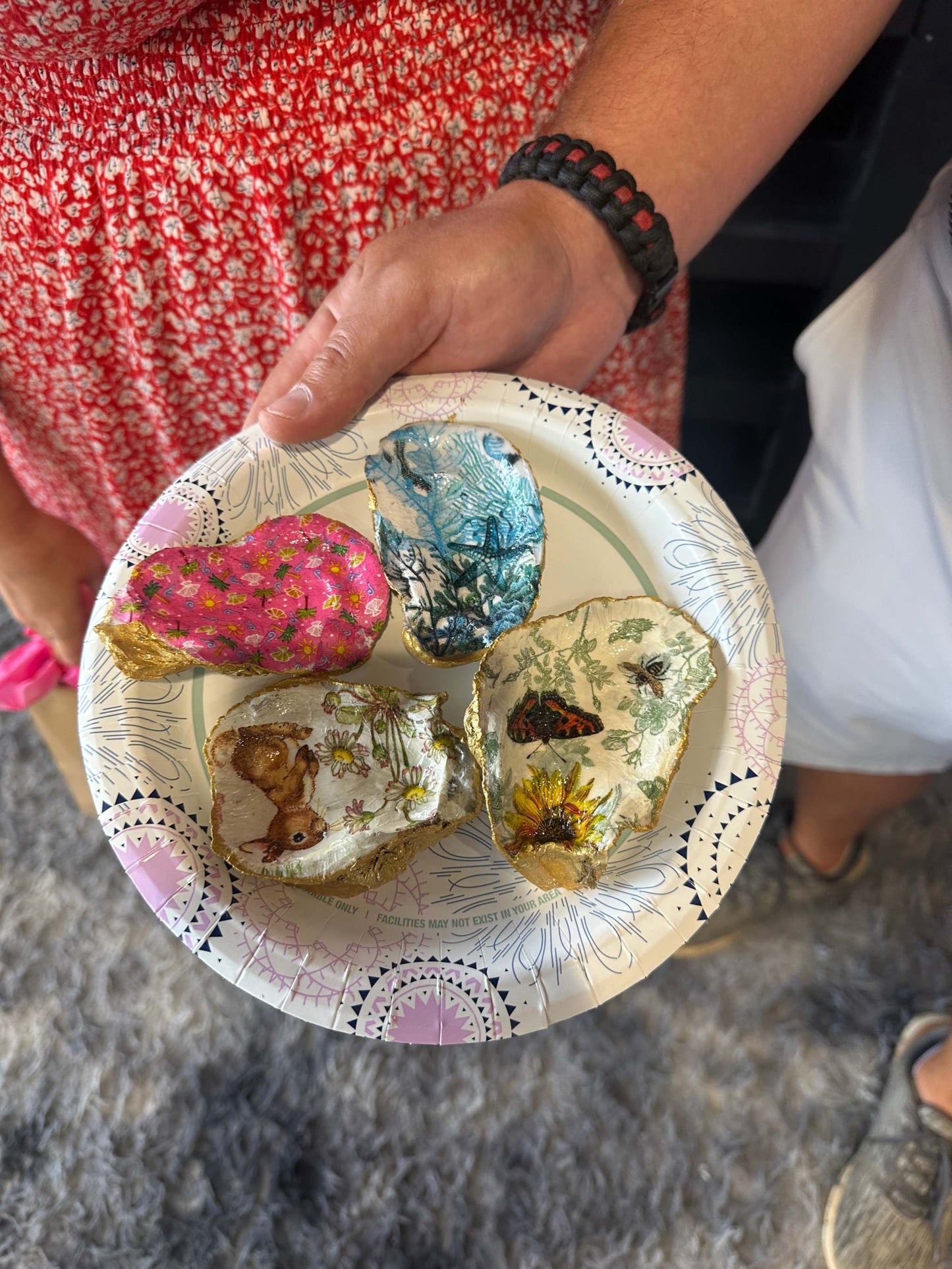 Person holding a decorative plate with nature-themed designs.